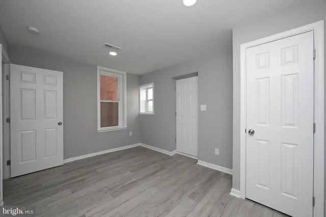 a view of an empty room with wooden floor and closet area