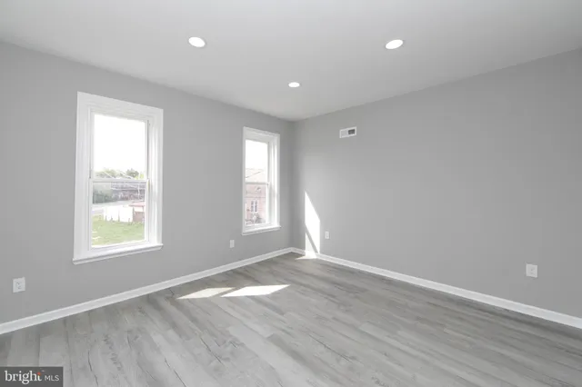 an empty room with wooden floor and windows