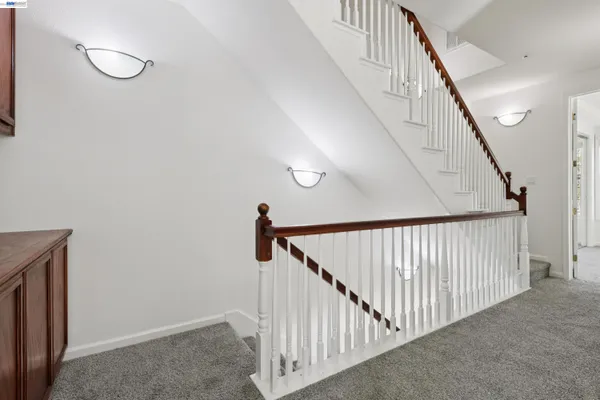 a view of staircase with railing and white walls