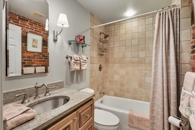 a bathroom with a granite countertop sink toilet and shower