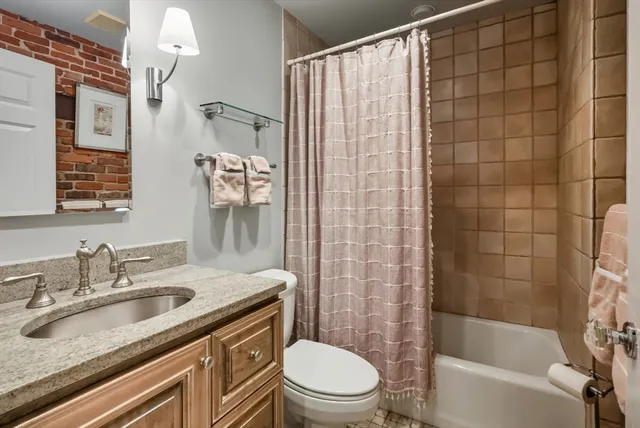 a bathroom with a granite countertop sink a toilet and shower