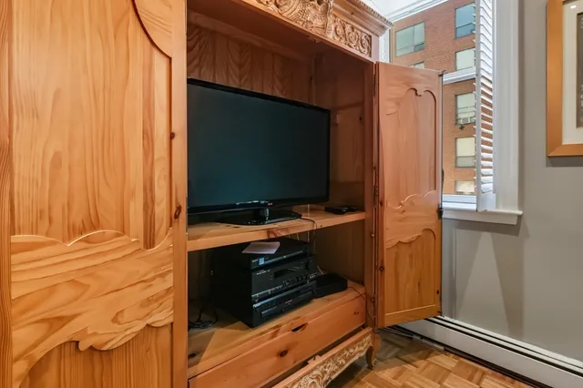 a living room with a flat screen tv on a dresser and a window