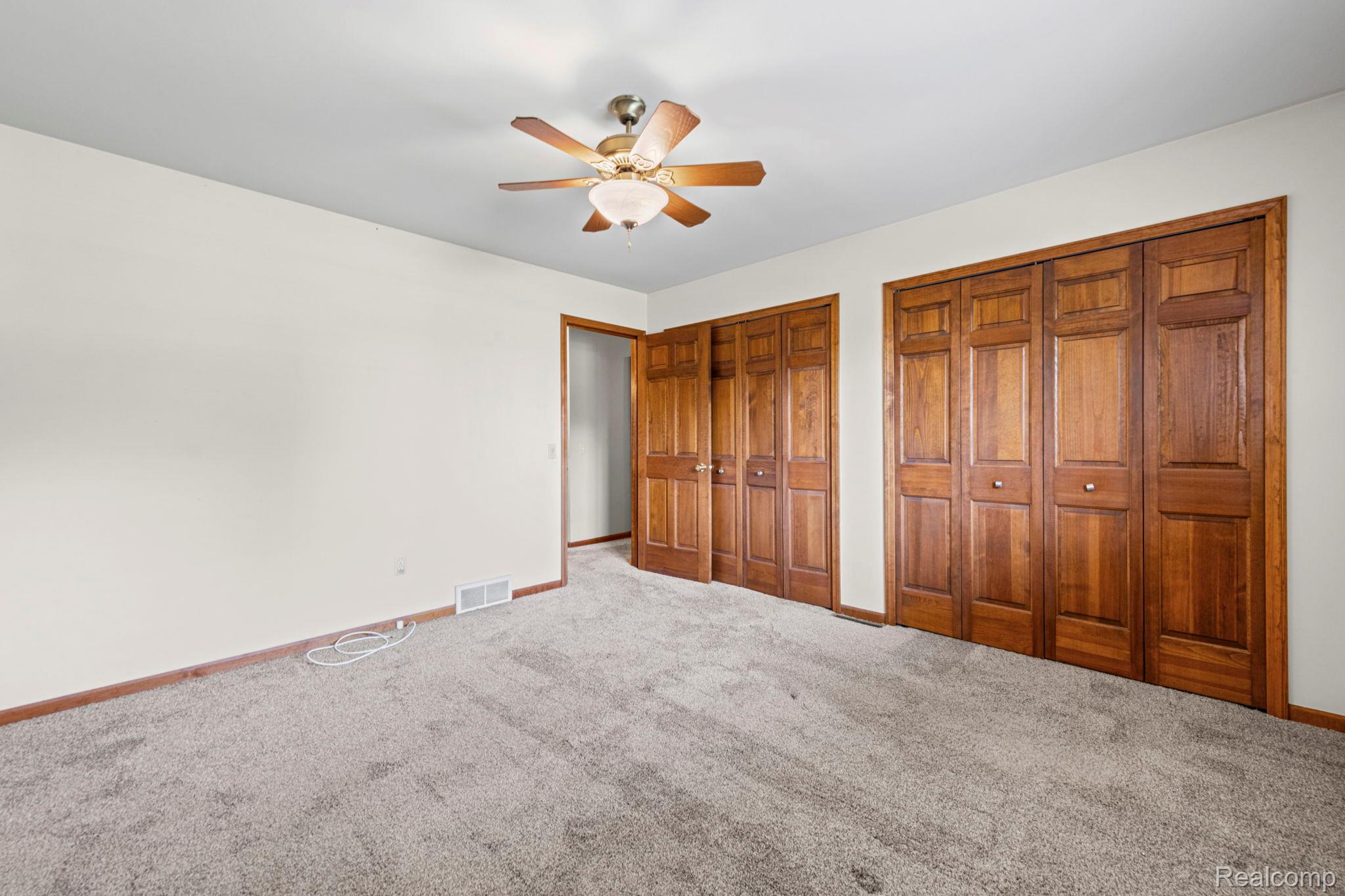 21580 Georgetown Road Trenton, MI 48183 - Photo 19 of 36 Room featuring light-toned walls, gray carpeting, a ceiling fan with integrated lighting, and multiple wood-panel bi-fold closet doors