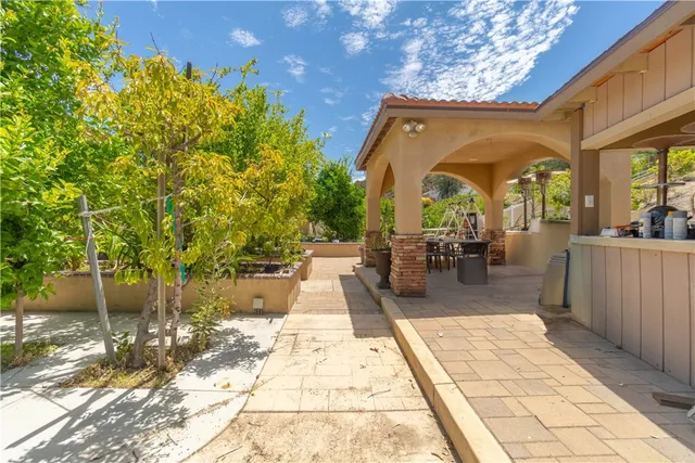 a view of a patio with table and chairs potted plants and large tree