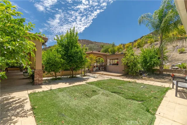 a backyard of a house with table and chairs under an umbrella