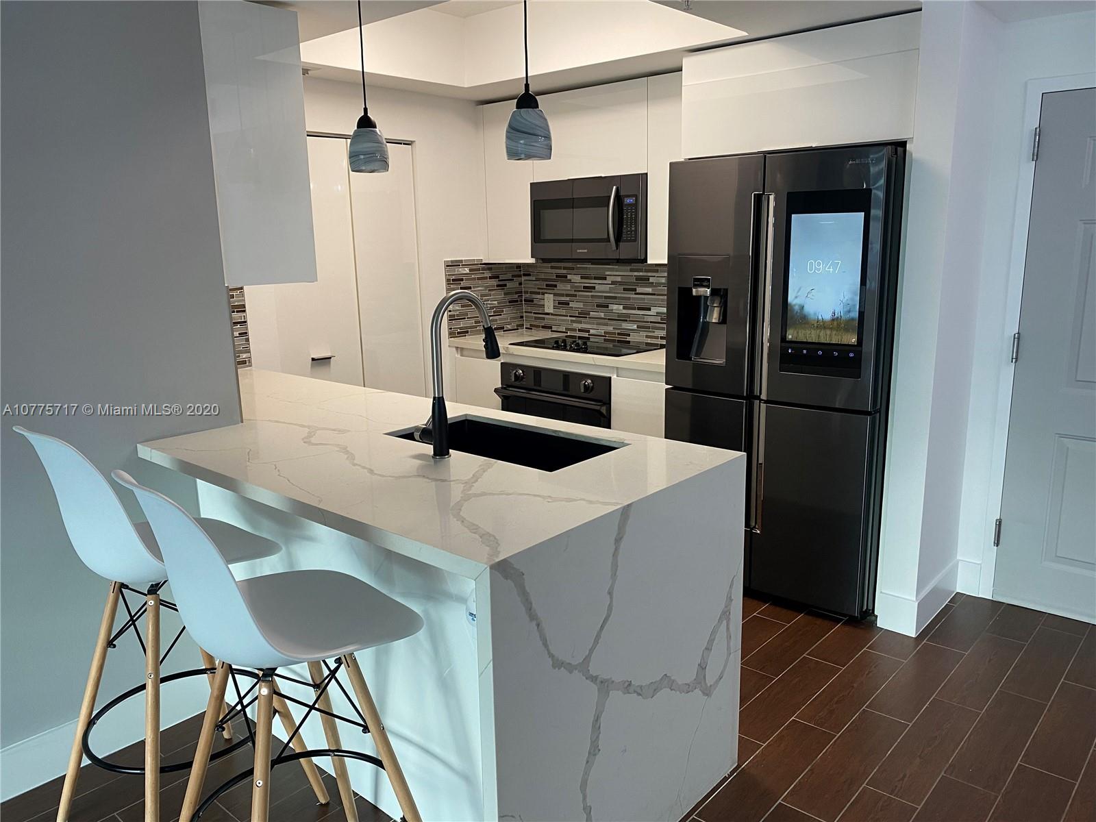 2000 North Bayshore Drive, Unit 407 Miami, FL 33137 - Photo 8 of 19 a kitchen with stainless steel appliances a stove a refrigerator and a microwave