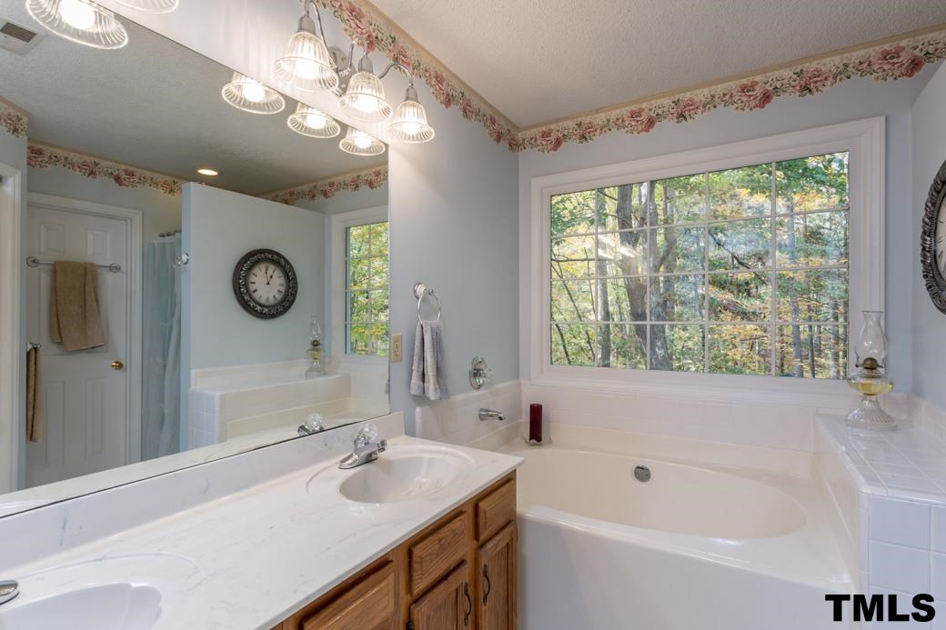 1241 Hillingdon Way Raleigh, NC 27614 - Photo 12 of 21 Master Bath features a double sink vanity, large soaker tub with private, wooded view, standing shower, toilet room, linen closet, and a CEDAR-LINED walk-in closet!