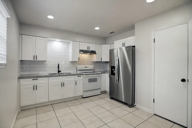 a kitchen with a refrigerator sink and cabinets