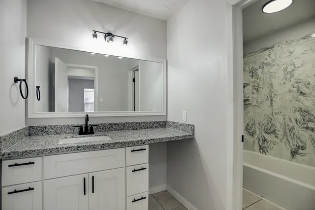 a bathroom with a granite countertop sink and a mirror