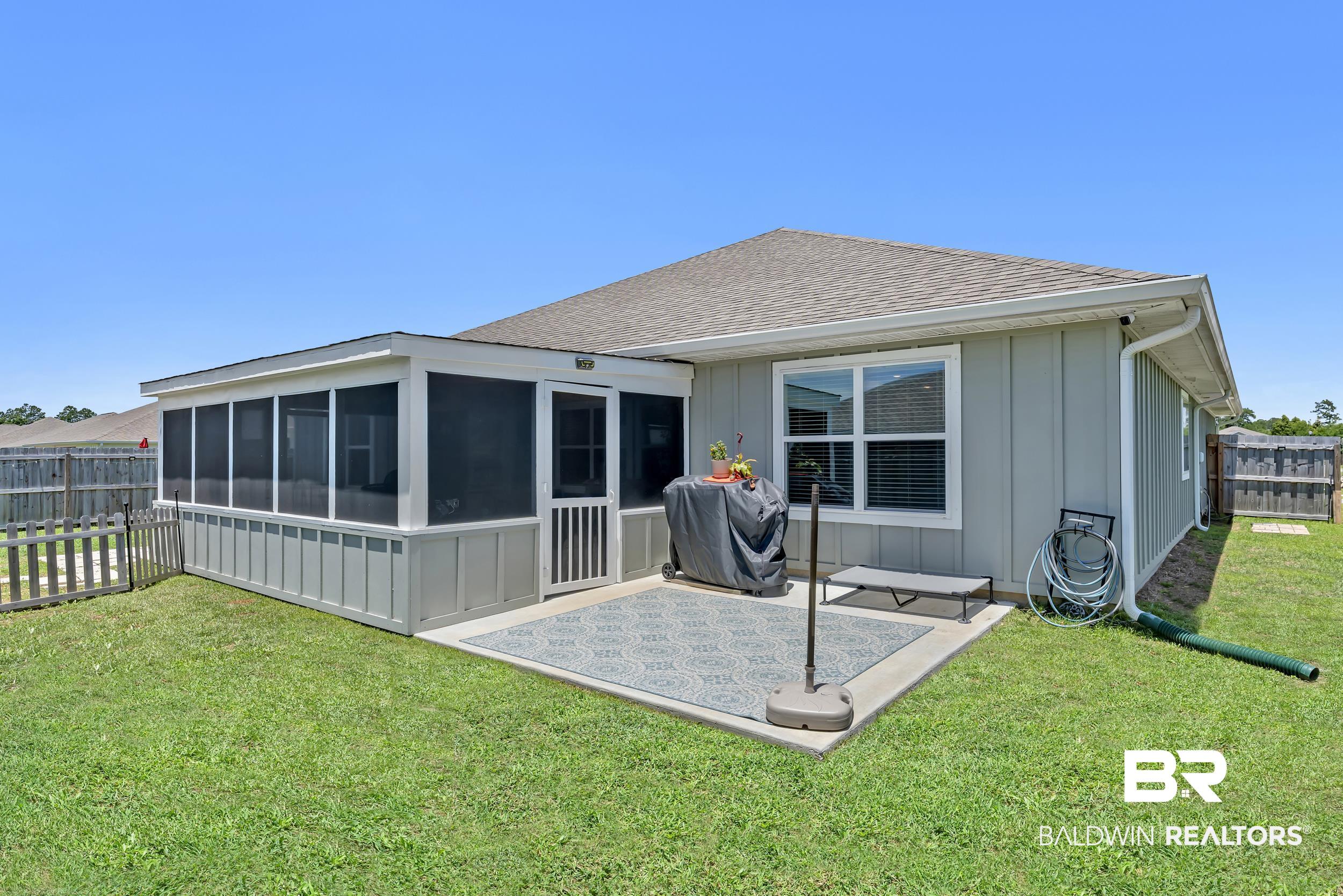 24271 Ringneck Loop Elberta, AL 36530 - Photo 43 of 44 Backyard featuring a screened-in porch with a panel door, concrete patio, and light gray siding