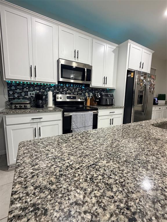 5684 Western Sun Drive St. Cloud, FL 34771 - Photo 8 of 16 a kitchen with stainless steel appliances kitchen island granite countertop a sink a stove a microwave and cabinets