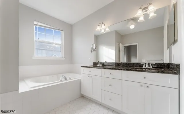 a bathroom with a granite countertop bathtub a sink and a mirror