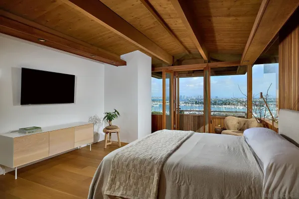 a bedroom with a bed and a flat tv screen next to a large window