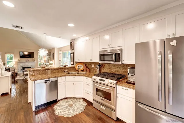 a kitchen with stainless steel appliances a stove a sink dishwasher a refrigerator and a stove with wooden floor