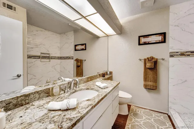 a bathroom with a granite countertop sink a toilet and mirror