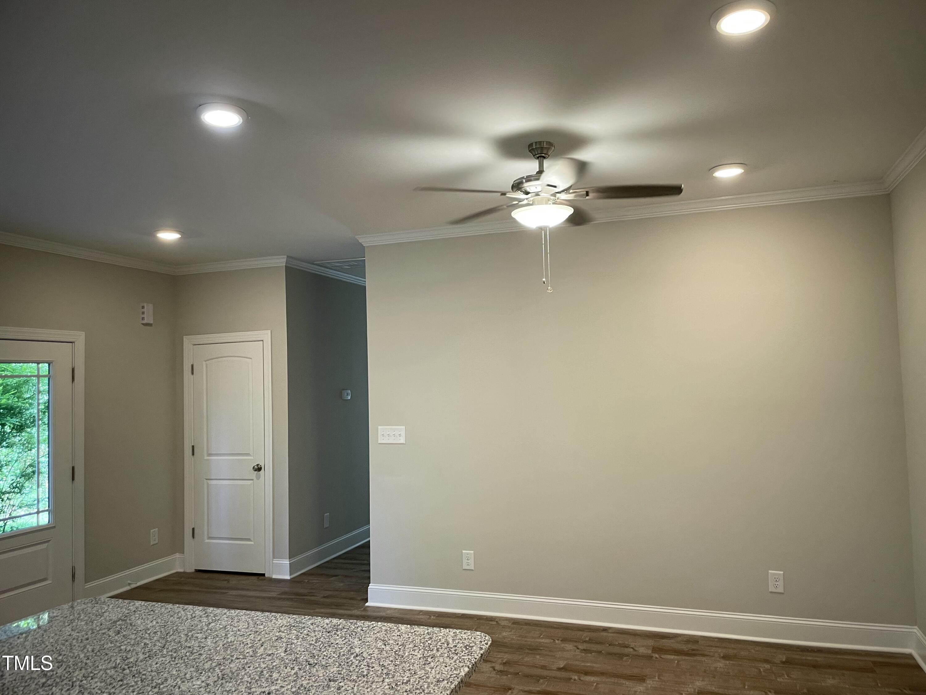 5500 Batoul Lane Raleigh, NC 27606 - Photo 7 of 32 an empty room with a chandelier fan and windows