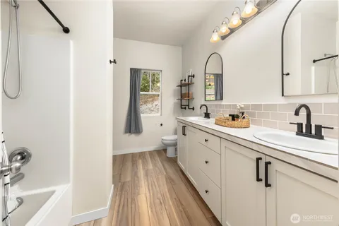 a spacious bathroom with a double vanity sink a mirror and a bathtub