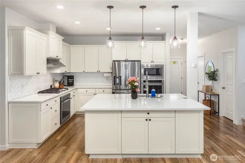 a kitchen with kitchen island granite countertop a sink a counter space appliances and cabinets