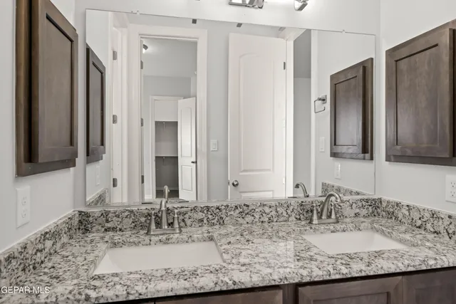 a bathroom with a granite countertop double vanity sink and a mirror