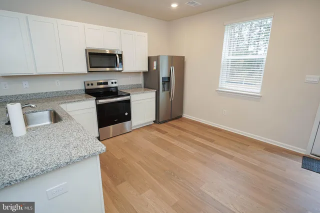 a kitchen with stainless steel appliances a refrigerator sink and wooden floor