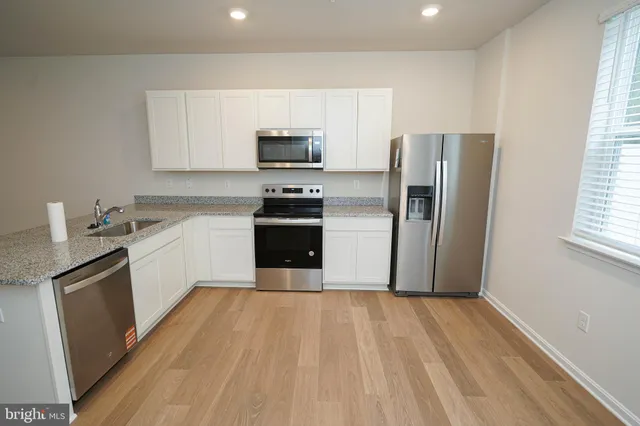 a kitchen with stainless steel appliances granite countertop a stove top oven a sink dishwasher a refrigerator and a microwave