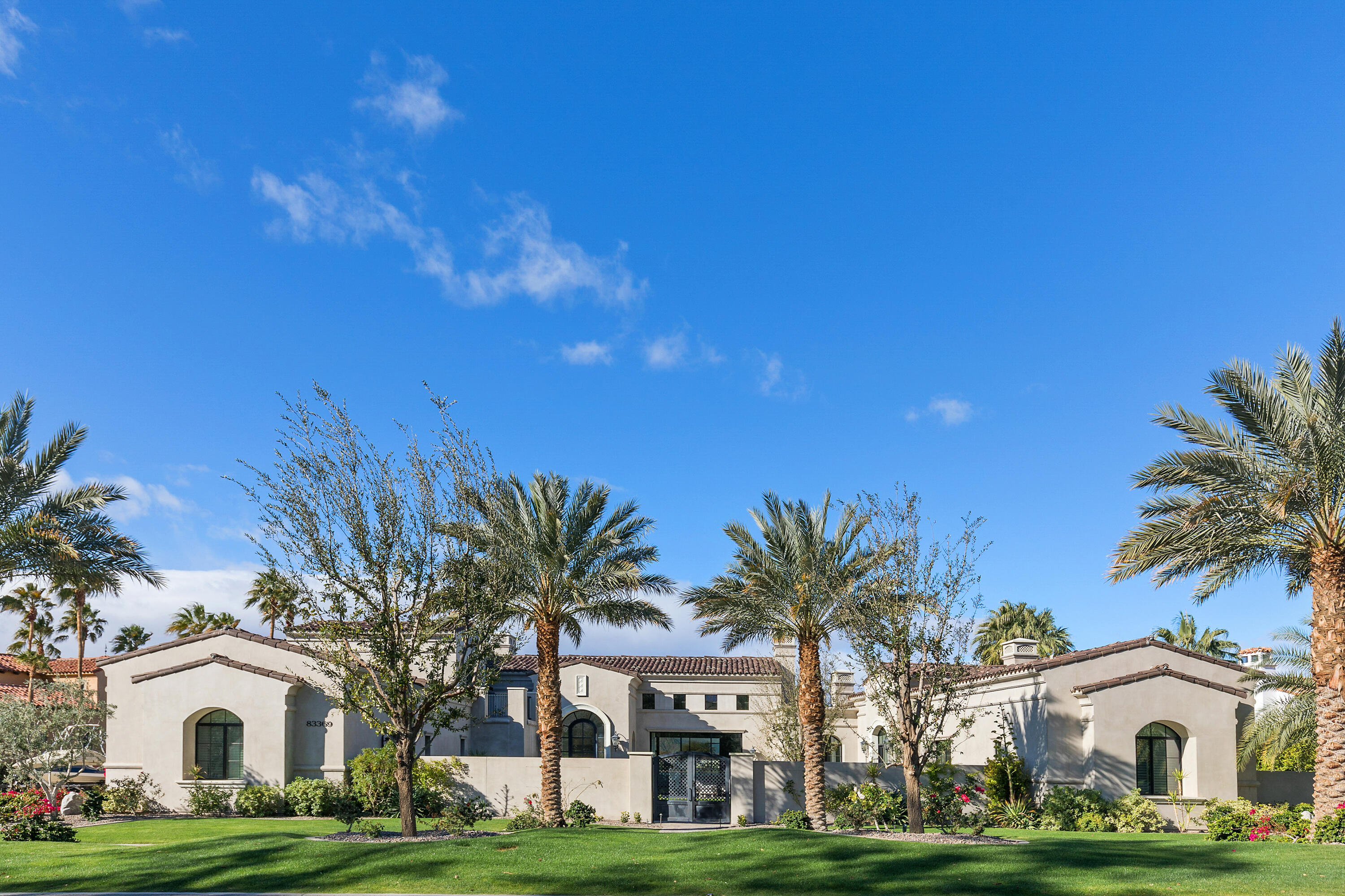 a view of white house with a big yard and palm trees