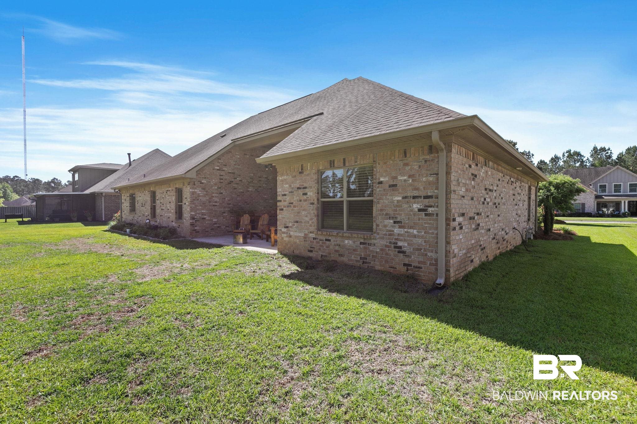31911 Bobwhite Road Daphne, AL 36527 - Photo 54 of 85 View of side of home with brick siding, a yard, a patio area, and a shingled roof