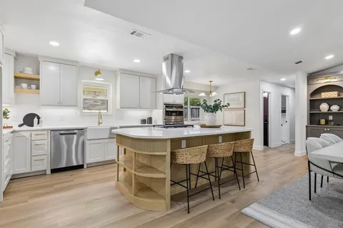 a kitchen with granite countertop a table chairs stove a sink and dishwasher