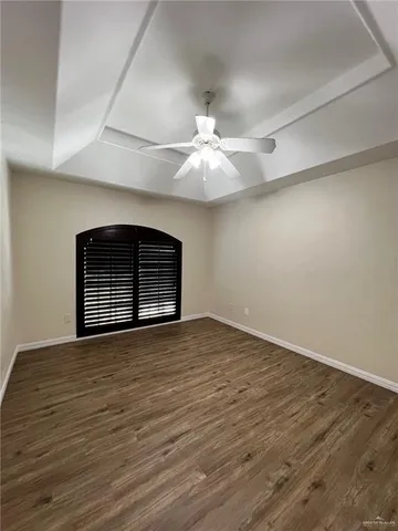 a view of an empty room with a fireplace and a ceiling fan