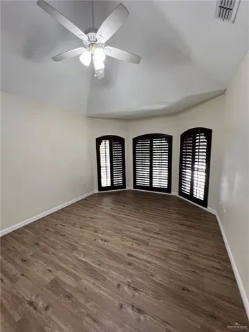a view of an empty room with window and wooden floor