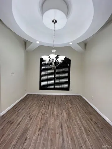 a view of a room with wooden floor chandelier and a window