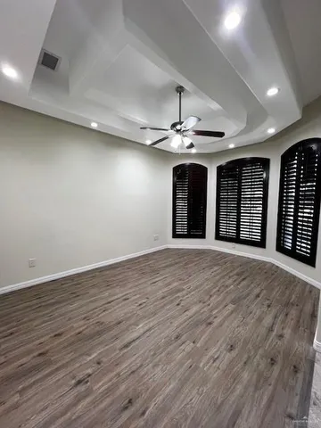a view of an empty room with wooden floor and chandelier