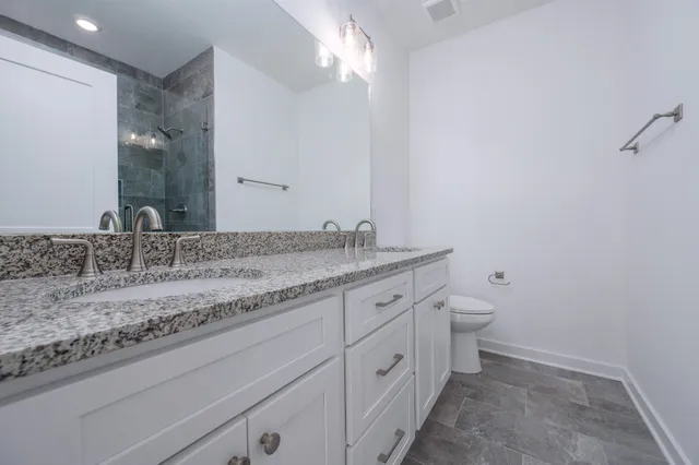 a bathroom with a granite countertop sink a toilet and a mirror