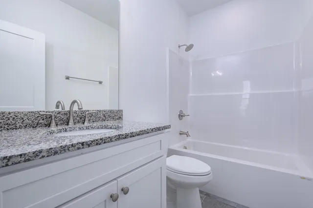 a bathroom with a granite countertop toilet a sink and a bathtub