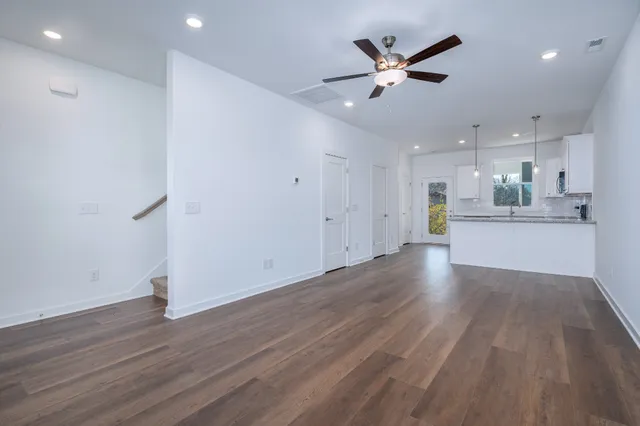 a view of an empty room with wooden floor and a ceiling fan