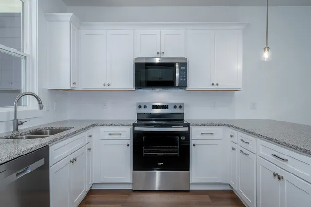 a kitchen with granite countertop white cabinets and stainless steel appliances