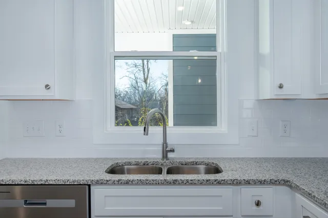 a kitchen with granite countertop white cabinets and window