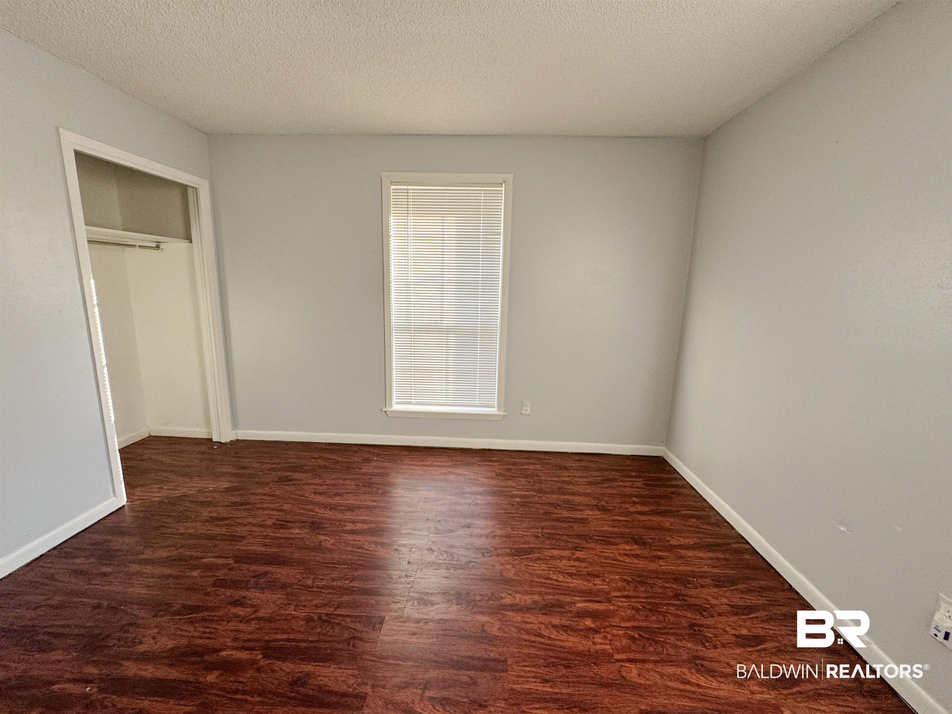 1227 Northgate Drive Atmore, AL 36502 - Photo 9 of 14 Unfurnished bedroom featuring dark wood-style flooring, a textured ceiling, and a closet