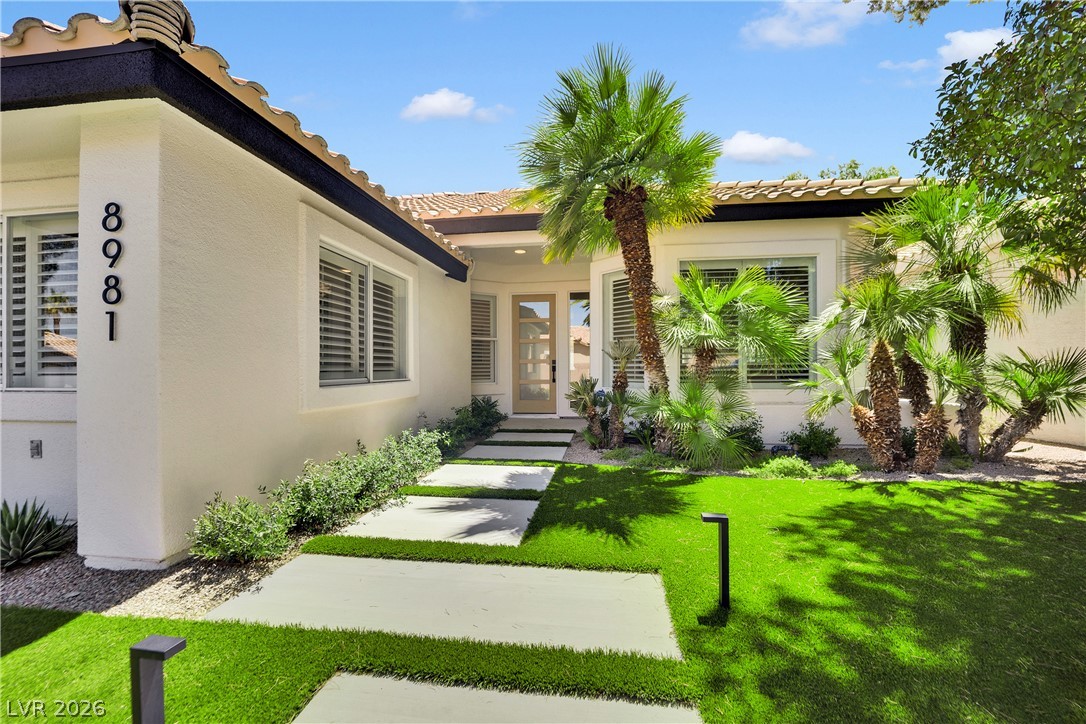 8981 Rivers Edge Drive Las Vegas, NV 89117 - Photo 5 of 69 A modern exterior welcomes with tropical foliage, a tiled roof, and a contemporary pathway.