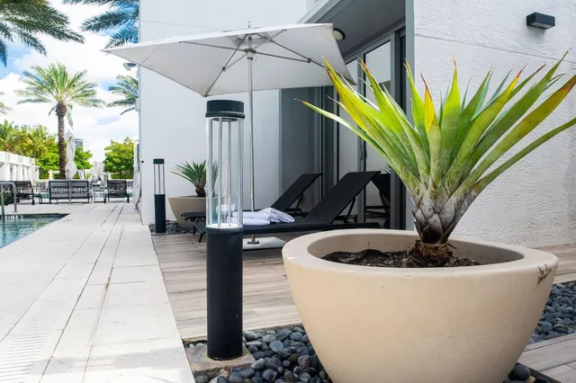 a view of a patio with table and chairs potted plants and floor to ceiling window and potted plants