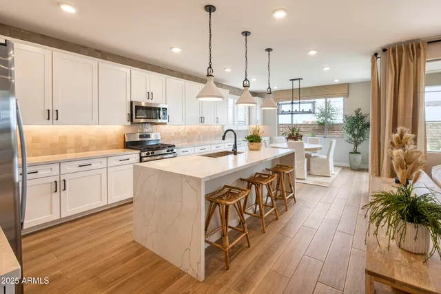 a kitchen with stainless steel appliances granite countertop a sink a stove and a wooden floors