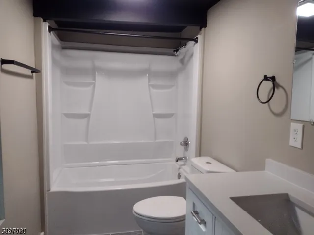a bathroom with a granite countertop bathtub shower sink vanity and toilet