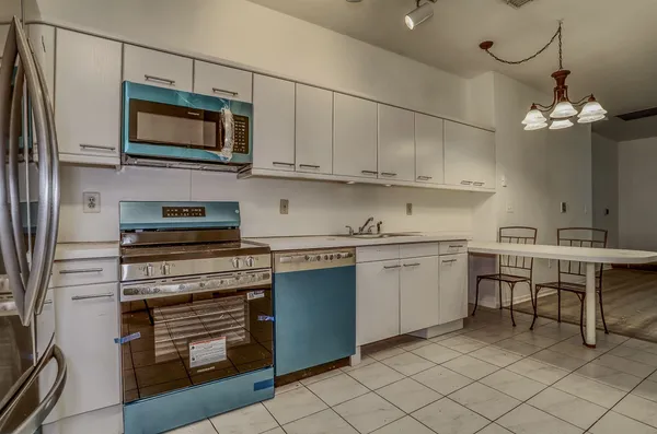 a kitchen with stainless steel appliances granite countertop a stove top oven a sink dishwasher and a microwave oven on the blue kitchen countertops