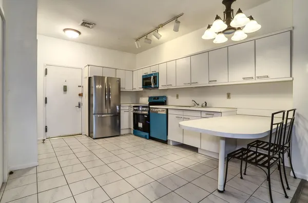 a kitchen with stainless steel appliances a sink a stove a refrigerator cabinets and a dining table