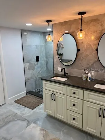 a bathroom with a granite countertop sink a mirror and shower