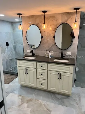 a bathroom with a granite countertop double vanity sink and mirror