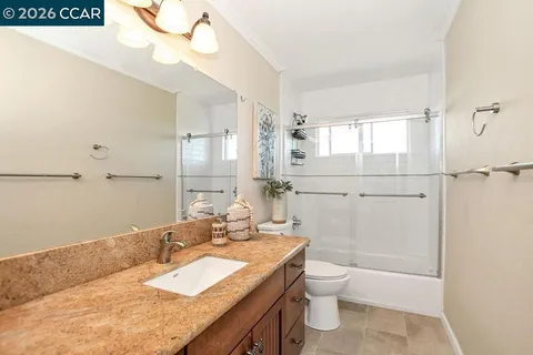a bathroom with a granite countertop sink toilet and shower
