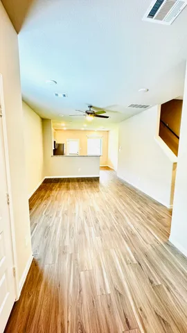 an empty room with wooden floor closet and windows