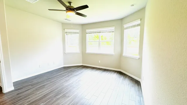 an empty room with wooden floor and windows