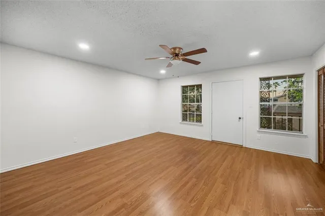 a view of an empty room with a window and wooden floor